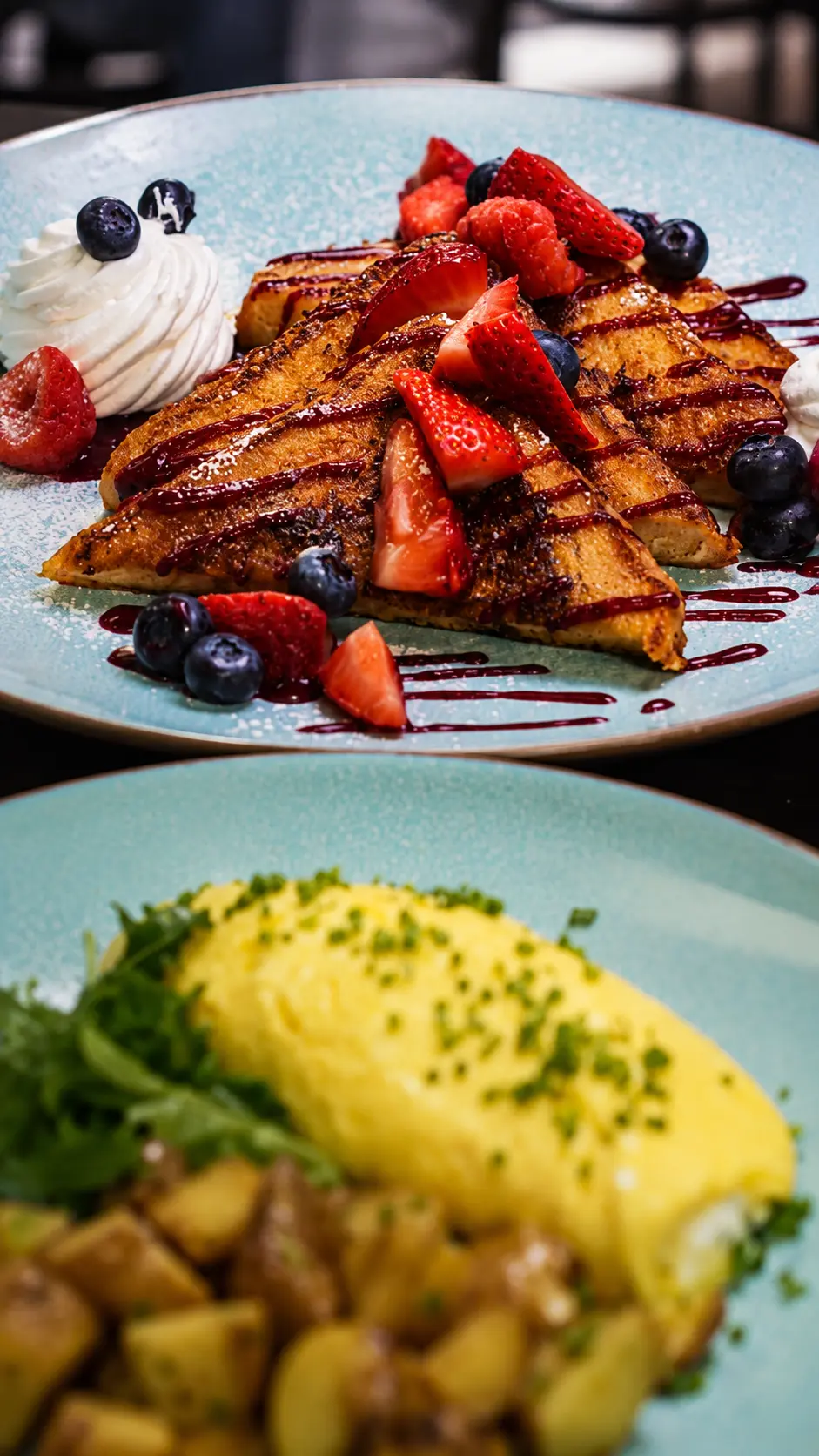 Miami brunch: French toast with berries and whipped cream, and a fluffy omelet with potatoes.