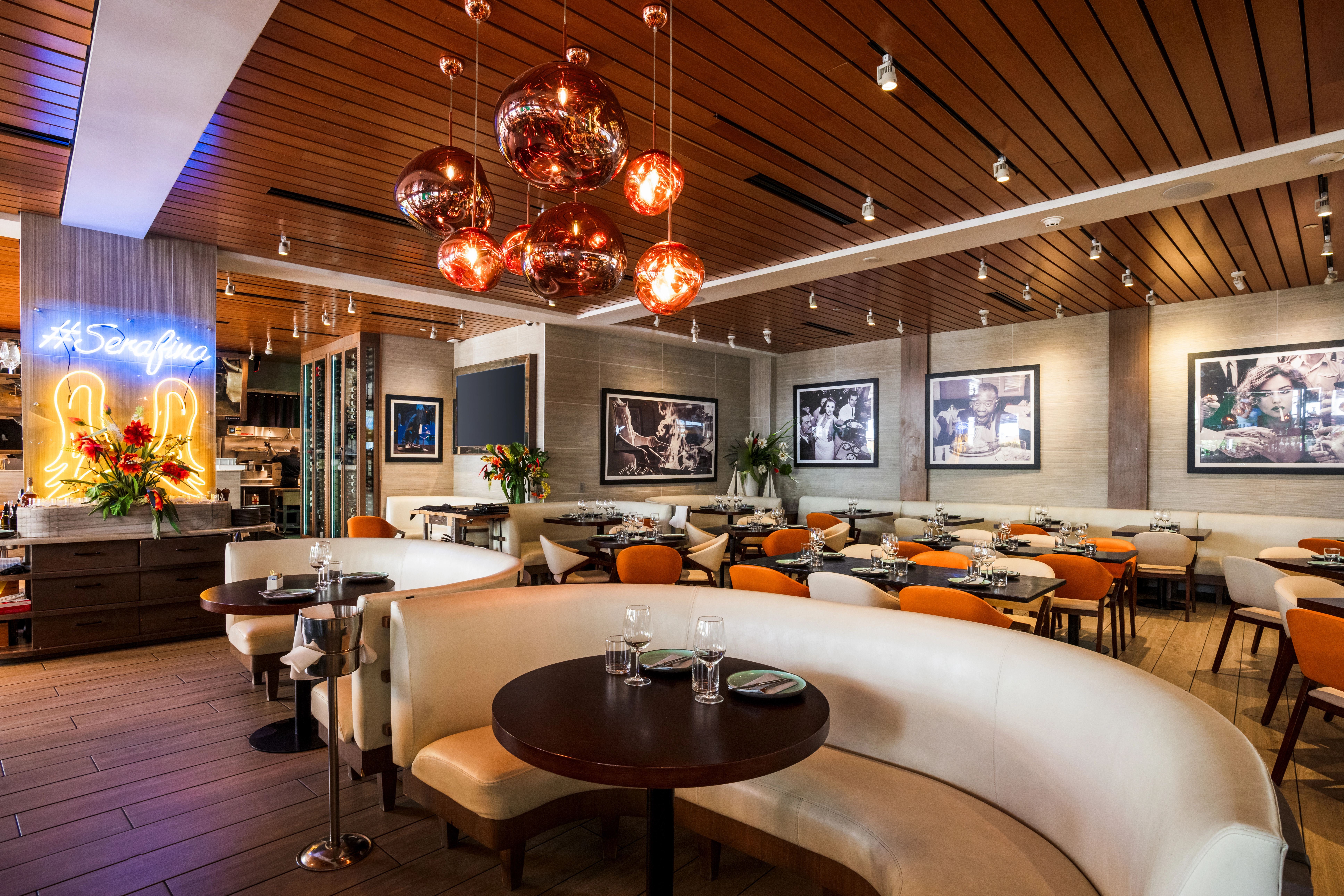 Interior of Aventura Mall restaurant with white banquettes and hanging lamps